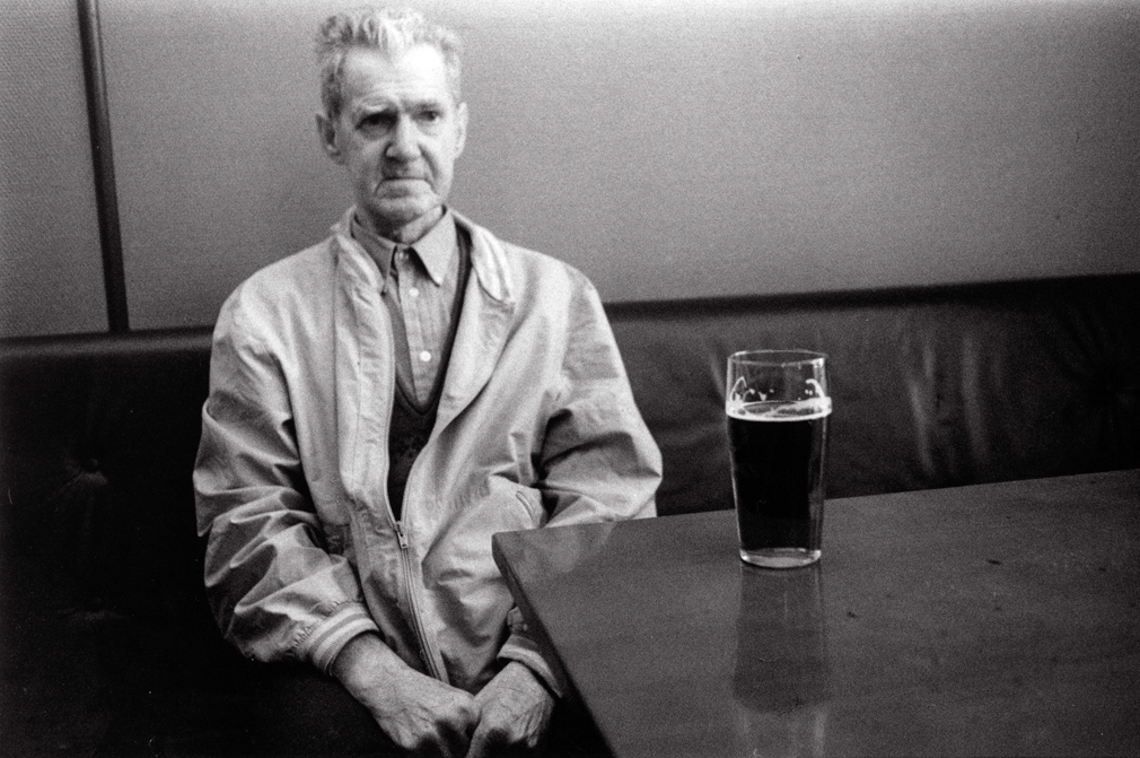 Man sits in a pub with beer glass in front of him on the table. Photo