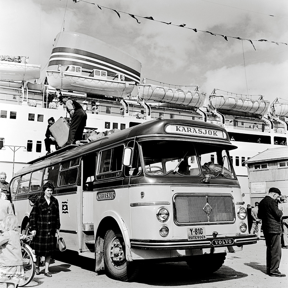 Buss på kai med folk som laster av vesker. Foto.